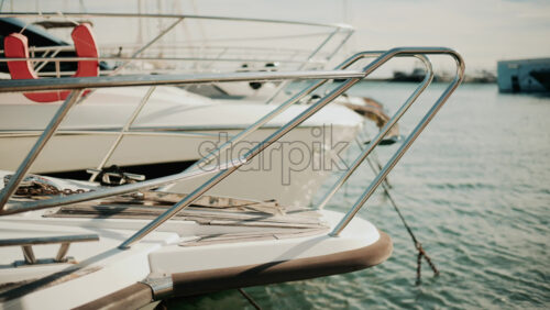 Video - Close up of chrome railing and wooden deck of a luxury yacht docked in a marina under golden light