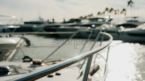 Video - Close up of chrome railing and wooden deck of a luxury yacht docked in a marina under golden light