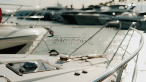 Video - Close up of chrome railing and wooden deck of a luxury yacht docked in a marina under golden light