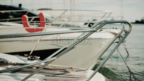 Video - Close up of chrome railing and wooden deck of a luxury yacht docked in a marina under golden light