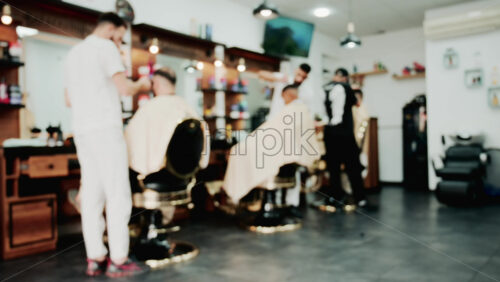 Video - Men getting haircuts in a modern barbershop with warm lighting and stylish decor