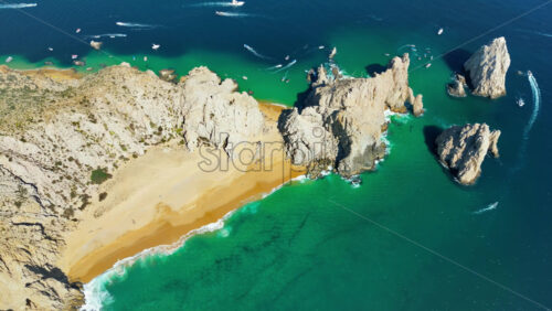 Video – Aerial drone view of Cabo San Lucas showing the bright turquoise water, white sand, and striking rock structures extending into the sea - Starpik Stock