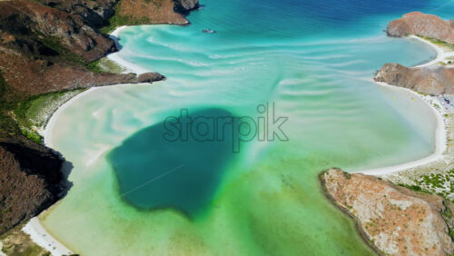Video – Aerial drone view of crystal clear blue waters with desert mountains in the background along the Baja California coast - Starpik Stock