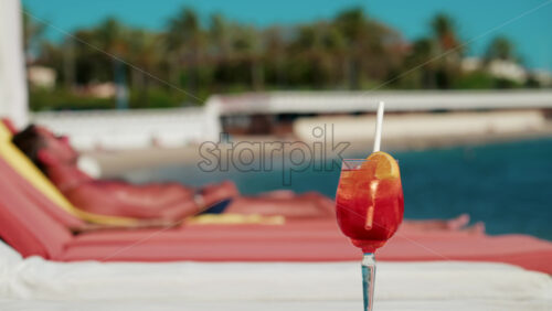 Video – Close up of a refreshing red orange cocktail with orange slice and ice cubes, captured outdoors on a sunny day in Cannes - Starpik Stock