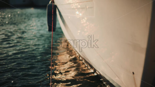 Video – Golden sunlight shimmering on the side of a yacht floating on calm water - Starpik Stock