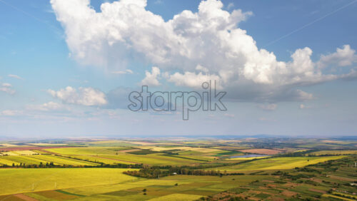 Video - Aerial drone view of the vast Moldovan countryside with colorful patchwork fields stretching to the horizon under a partly cloudy sky
