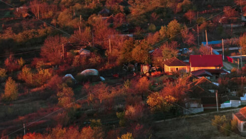 Video - Aerial drone view of colorful autumn trees and traditional Moldovan houses bathed in sunset light