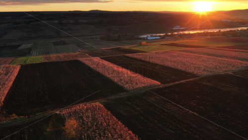 Video - Aerial drone view showing the Moldovan countryside at sunset with farmland patterns and a glowing river in the distance