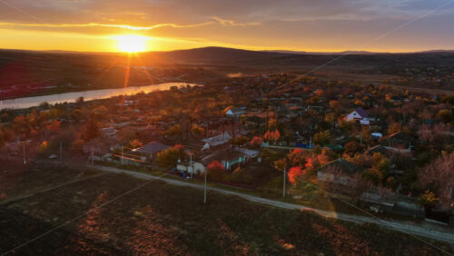 Video - Aerial drone view showing the Moldovan countryside at sunset with farmland patterns and a glowing river in the distance