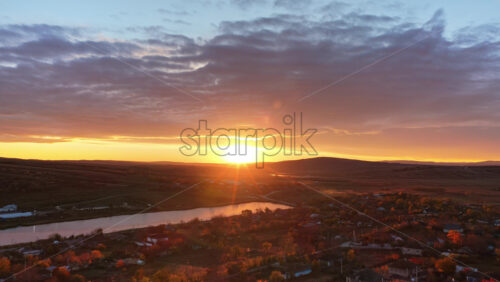 Video - Aerial drone view showing the Moldovan countryside at sunset with farmland patterns and a glowing river in the distance