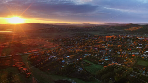 Video - Aerial drone view of a Moldovan village surrounded by autumn trees and farmlands during sunset