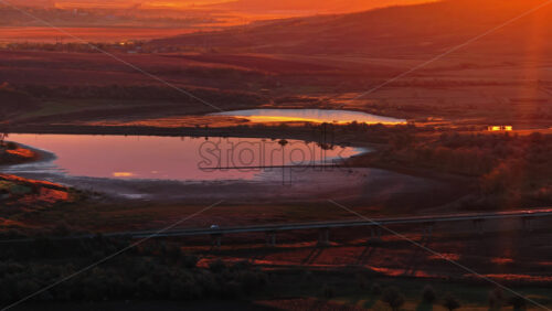 Video - Aerial drone view of a tranquil lake reflecting the warm golden light of sunset in rural Moldova