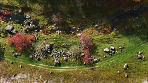 Video - Aerial drone view of a Moldovan valley with red autumn trees, rocks, and a small stream