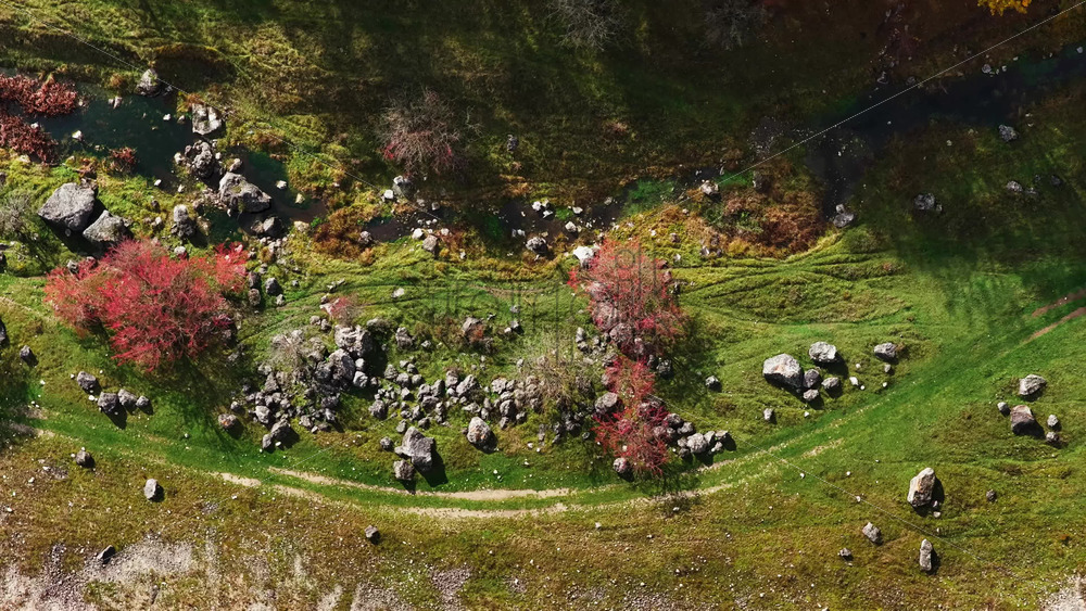 Video - Aerial drone view of a Moldovan valley with red autumn trees, rocks, and a small stream