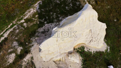 Video - Aerial drone view of a large white chalk rock formation rising from flat Moldovan fields