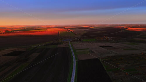 Video - Aerial drone view of a Moldovan village at sunset with the river and fields glowing in warm orange tones
