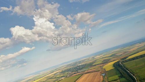 Video - Aerial drone view of the vast Moldovan countryside with colorful patchwork fields stretching to the horizon under a partly cloudy sky