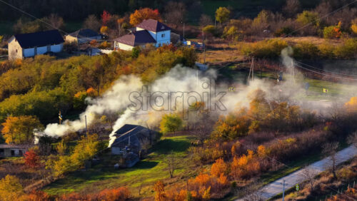 Video - Aerial drone view of smoke rising from farmlands in Moldova at golden hour