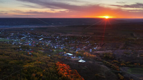 Video - Aerial drone view of the sun setting over a Moldovan village surrounded by farmlands
