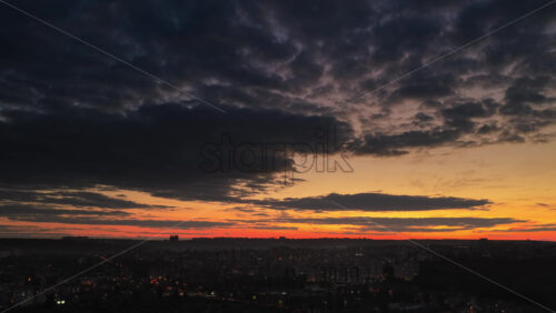 Video - Aerial drone view of Chisinau, Moldova at dusk with dark clouds and a glowing orange horizon