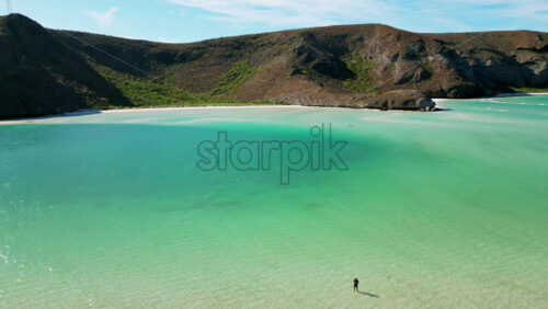 Video - Aerial drone view of crystal clear blue waters with desert mountains in the background along the Baja California coast