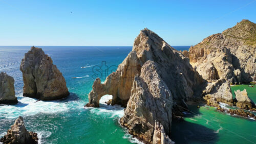 Video - Aerial drone view of the majestic Arch and surrounding cliffs of Cabo San Lucas under clear blue skies