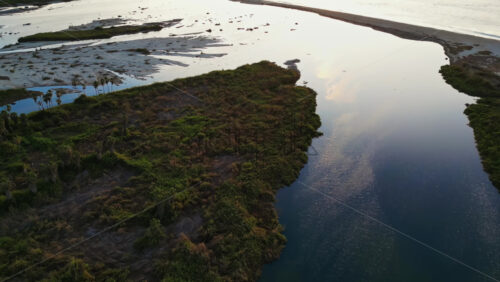 Video - Aerial drone view of wetlands in Baja California at sunset, with calm waters reflecting the soft sky colors