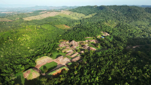 Video - Aerial drone view of ancient Mayan ruins hidden within a dense green jungle