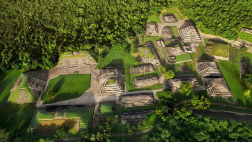 Video - Aerial drone view of ancient Mayan ruins hidden within a dense green jungle