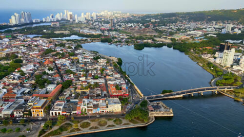 Video - Aerial drone view of Cartagena's colonial old town surrounded by the sea, with yachts anchored in the bay and the modern skyline in the distance