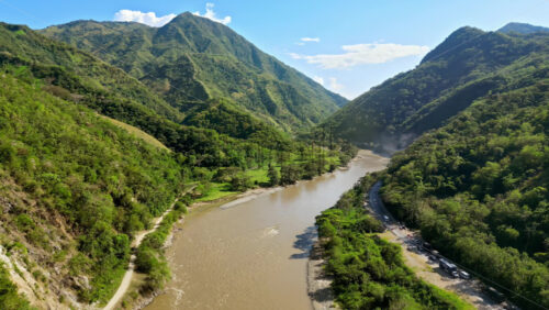 Video - Aerial drone view of the Magdalena River winding through lush green valleys and steep mountain slopes in Colombia