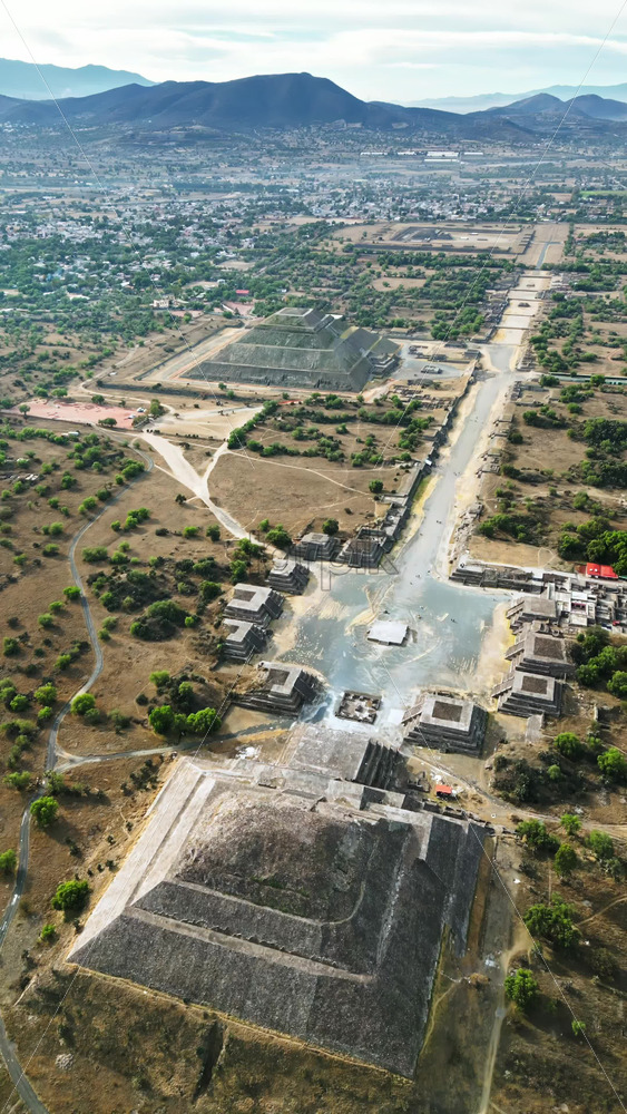 Video - Aerial drone view of the ancient Teotihuacan pyramids with the surrounding Mexican town and mountain landscape. Vertical