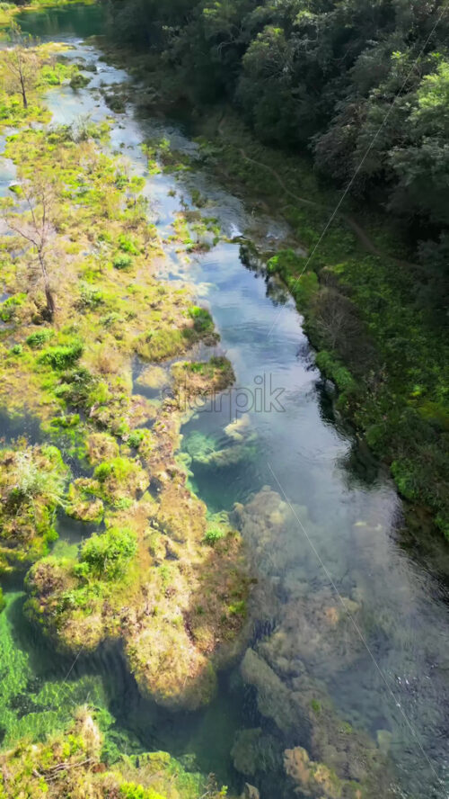 Video - Aerial drone view of a stunning canyon with turquoise waterfalls and layered rock formations surrounded by green forest in Mexico. Vertical