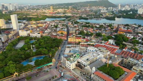 Video - Aerial drone view of Cartagena's city center with a large green park, colonial and modern buildings, and the Caribbean Sea in the background in slow motion