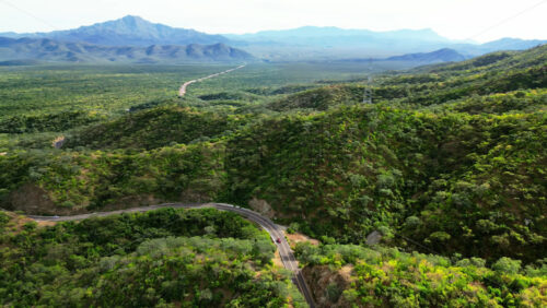 Video - Aerial drone view of a curved road passing through green mountains in Mexico in slow motion