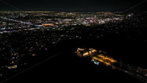 Video - Aerial drone view of Los Angeles shining under the night sky, with the downtown skyline surrounded by glowing streets and traffic
