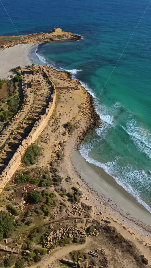 Video - Aerial drone view of the coastal ruins of Leptis Magna, an ancient Roman city in Libya. Vertical