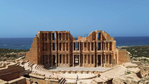 Video - Aerial drone view of the magnificent Roman Theatre of Sabratha, highlighting the detailed columns, arches, and stage area of the ancient structure