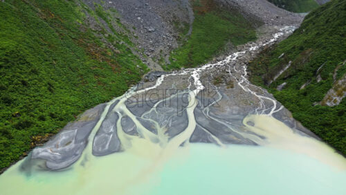 Video - Aerial drone view of a glacier melt river with intricate channels flowing into a turquoise lake