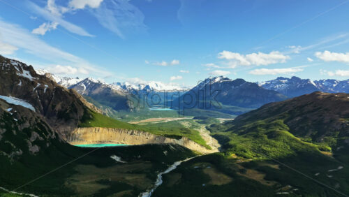 Video - Aerial drone view of a wide valley framed by snow capped Andes mountains and glacial rivers