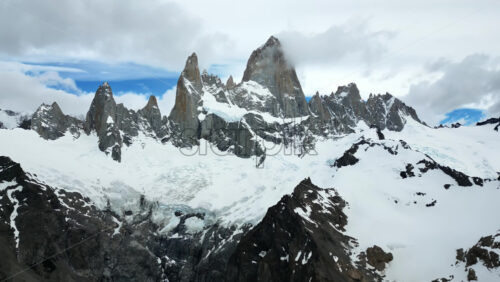 Video - Aerial drone view of two deep blue glacial lakes separated by rocky ridges and surrounded by snow covered mountains