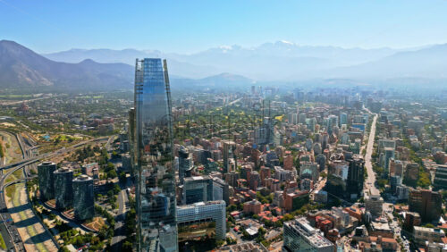 Video - Aerial drone view over Santiago's financial district with the Costanera Center and green areas visible on a clear day