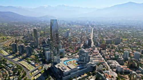 Video - Aerial drone view over Santiago's financial district with the Costanera Center and green areas visible on a clear day