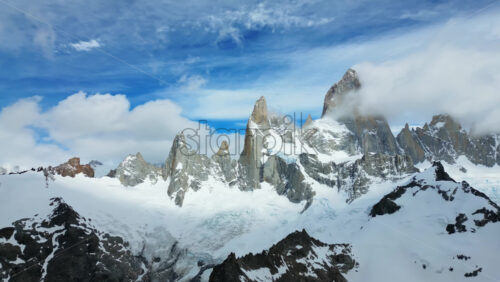 Video - Aerial drone view of two deep blue glacial lakes separated by rocky ridges and surrounded by snow covered mountains in slow motion