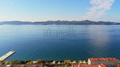 Video – Aerial drone view a cluster of terracotta roofed buildings near the waterfront, with trees and a central plaza. Zadar, Croatia - Starpik Stock