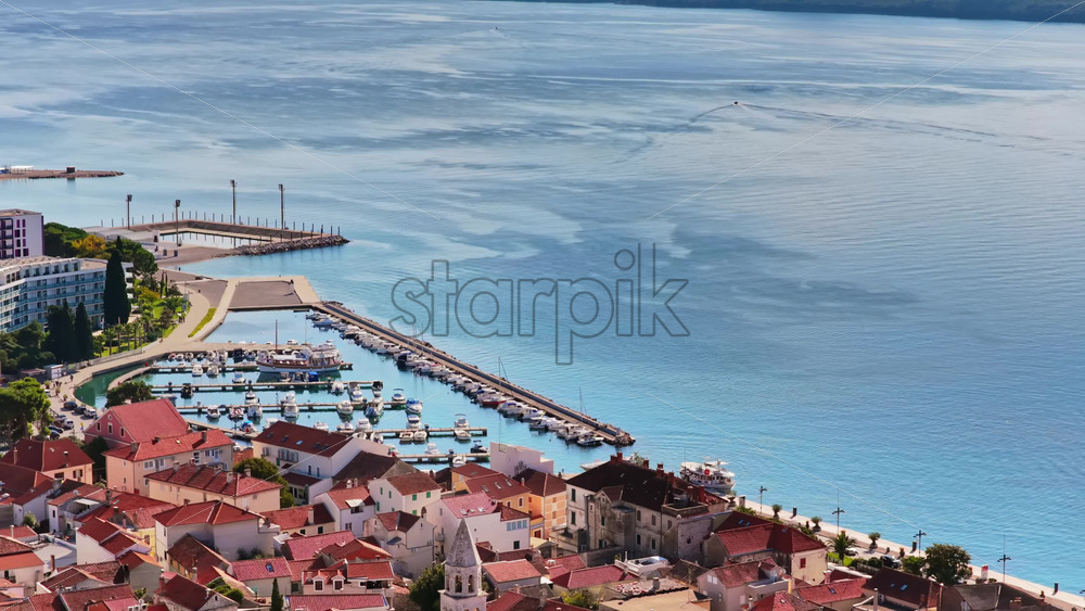 Video – Aerial drone view of Biograd’s residential area near the marina, showing clusters of red roofed homes with the harbor and anchored boats visible in the background. Biograd na Moru, Croatia - Starpik Stock