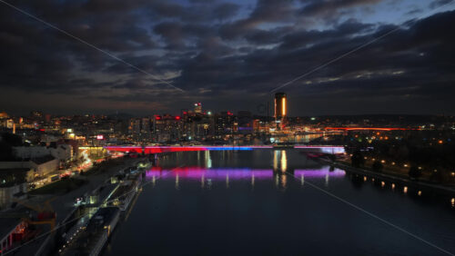 Video – Aerial drone view of Branko’s Bridge in Belgrade, Serbia, illuminated in colorful lights reflecting off the Sava River. - Starpik Stock