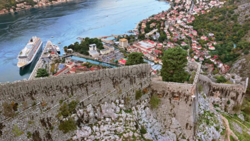 Video – Aerial drone view of Kotor’s ancient fortress walls perched on the mountainside, overlooking the town and the bay far below - Starpik Stock