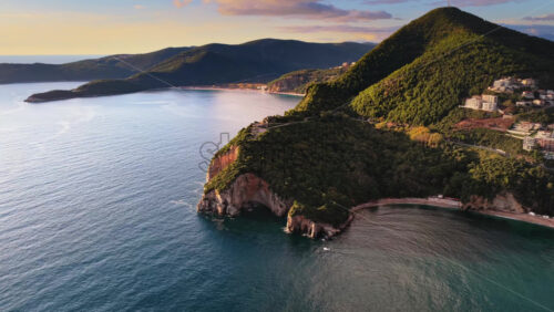 Video – Aerial drone view of Mogren or Slovenska Plaza area, showing a rocky peninsula jutting into the sea. Montenegro - Starpik Stock