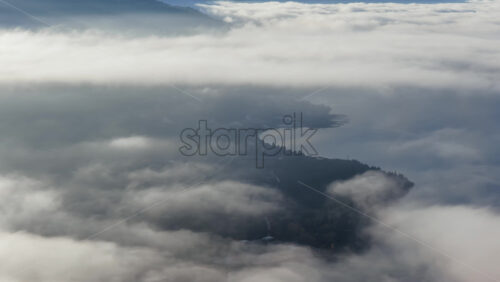 Video – Aerial drone view of Ohrid city partially obscured by drifting fog, with the marina and waterfront emerging from the mist while the mountains loom in the distance. - Starpik Stock